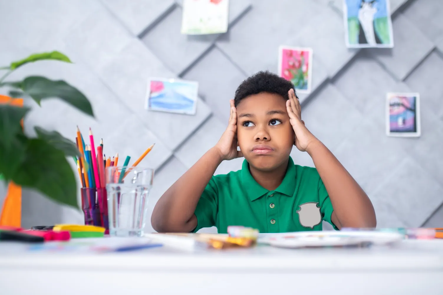 Boy touching head with hands looking pensively aside